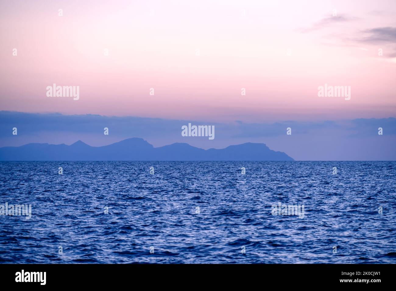 Sunset of ocean water with an island in the background Stock Photo