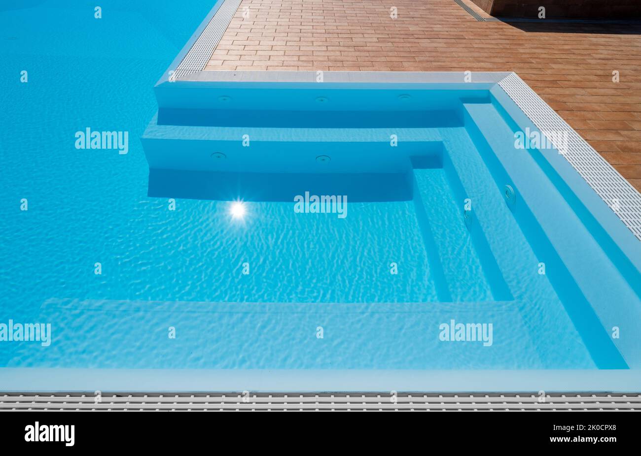 Swimming pool with steps in the jacuzzi corner with sun reflection Stock Photo