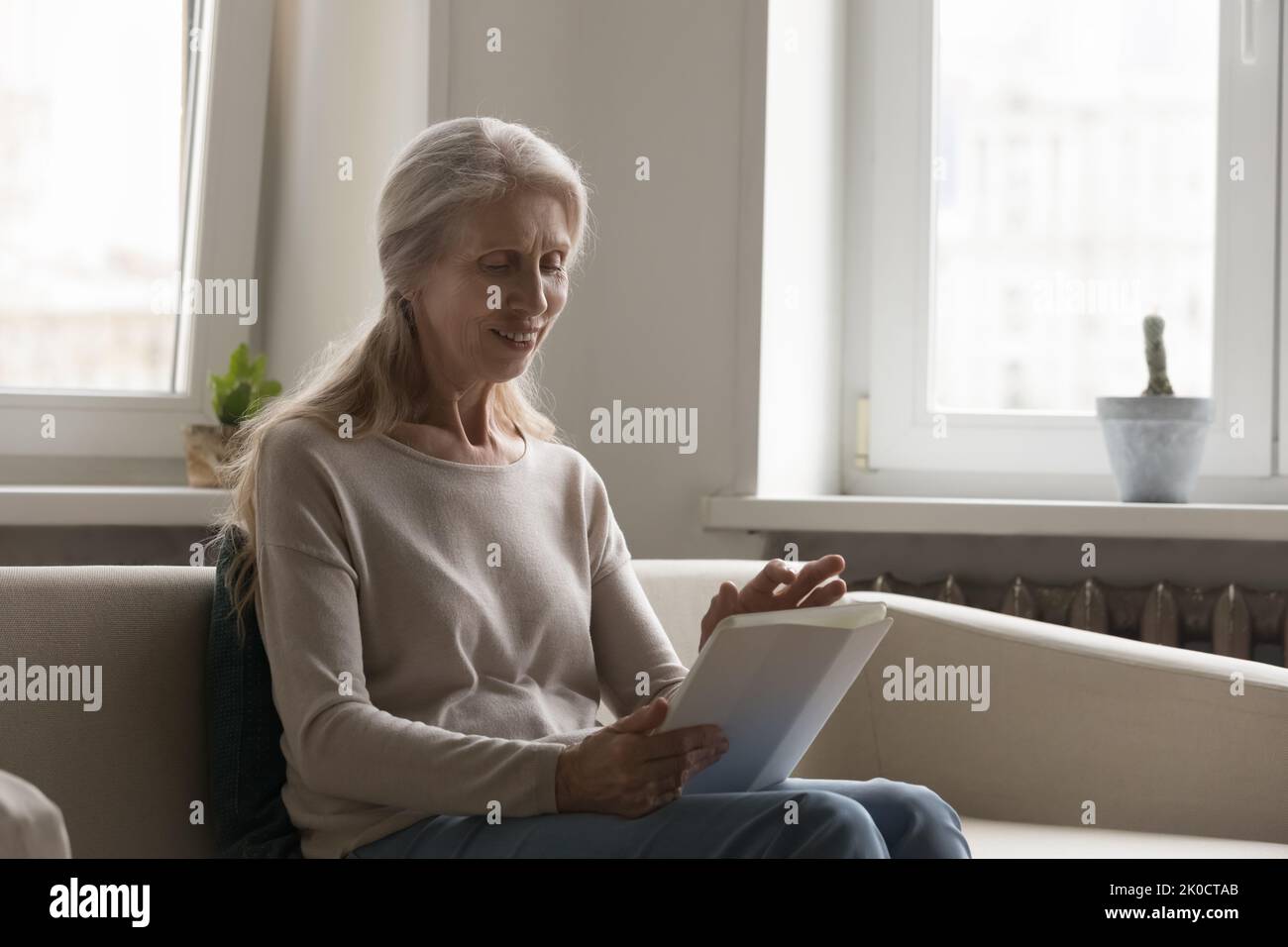 Happy retired tablet user lady using online virtual app Stock Photo