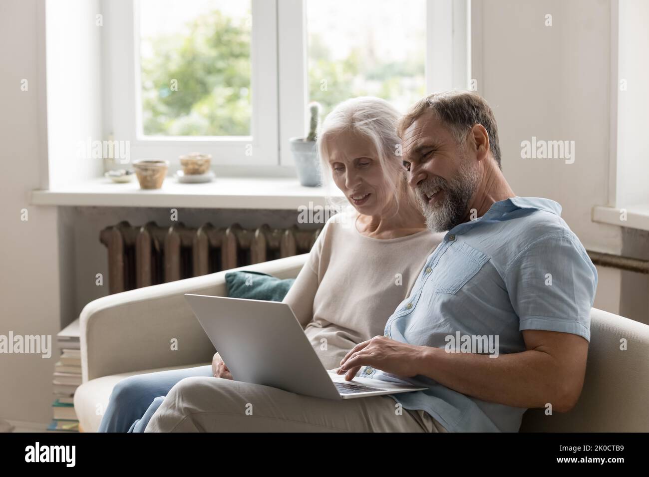 Cheerful older 60s married couple sitting on home sofa Stock Photo