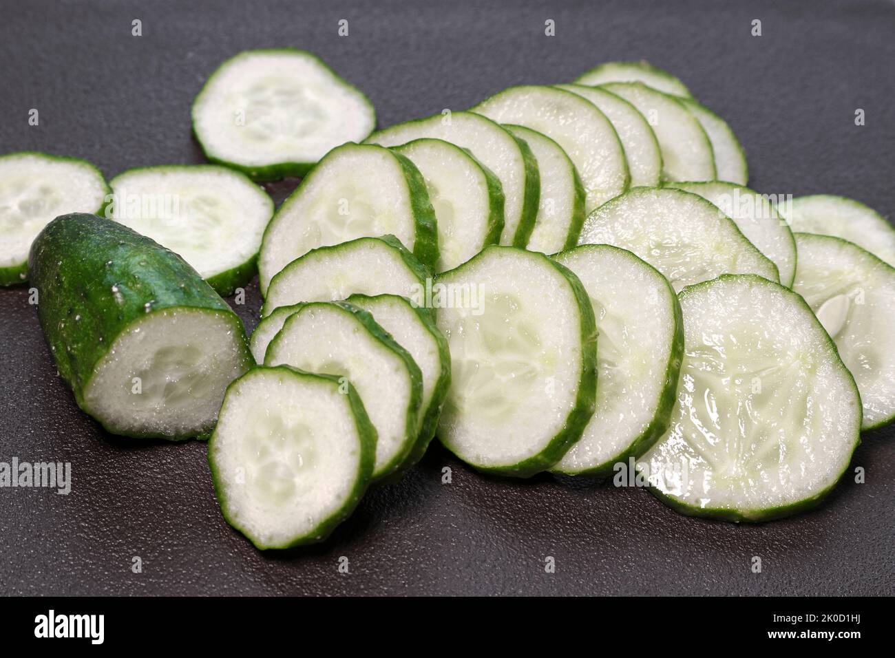 Sliced fresh cucumber for salad on a cutting board. Healthy vegetarian food. Ripe vegetables. Stock Photo