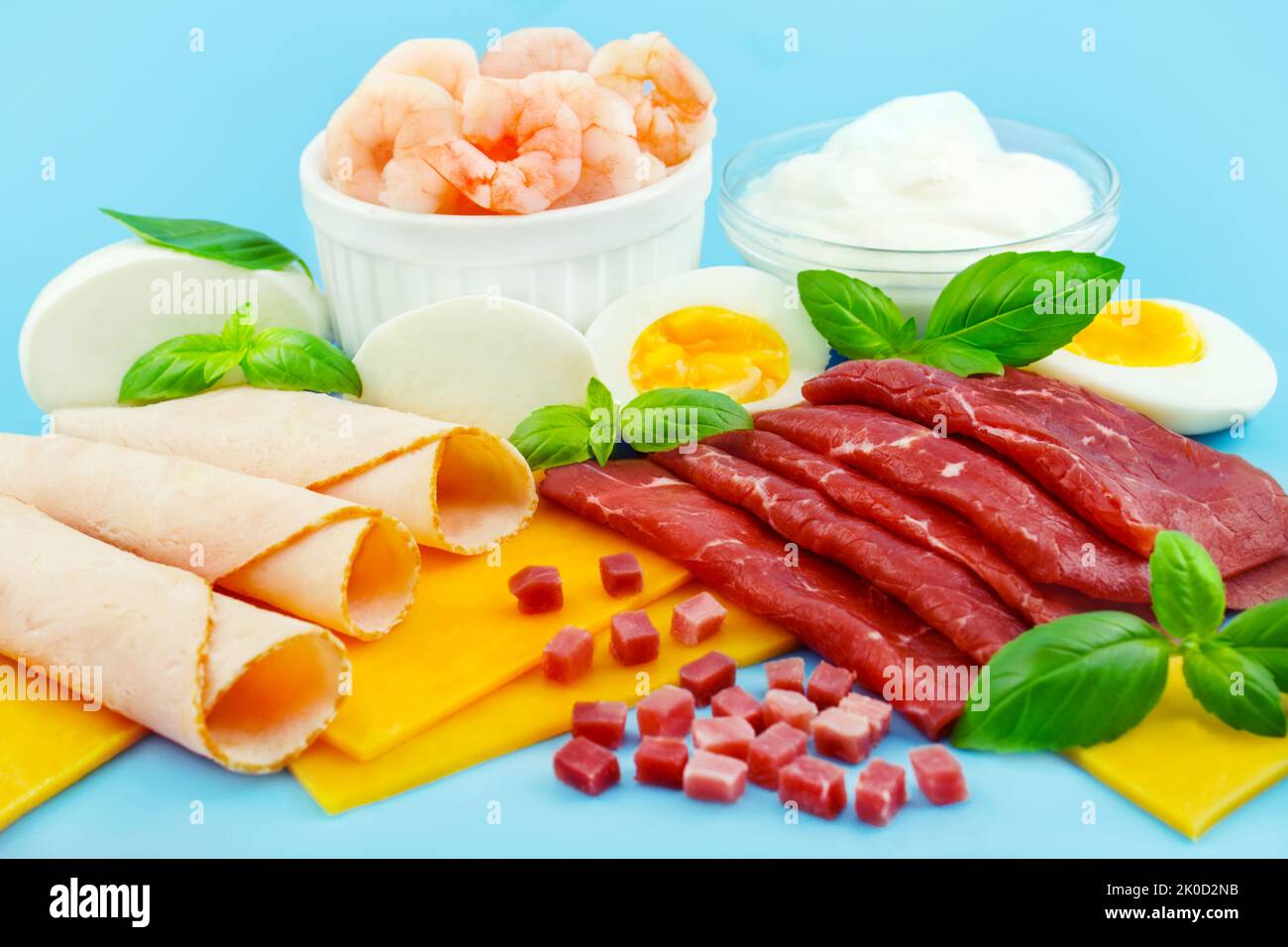 Proteinreiche Ernährung mit Fleisch, Käse, Ei, Joghurt und Shrimps auf blauem Hintergrund Stock Photo