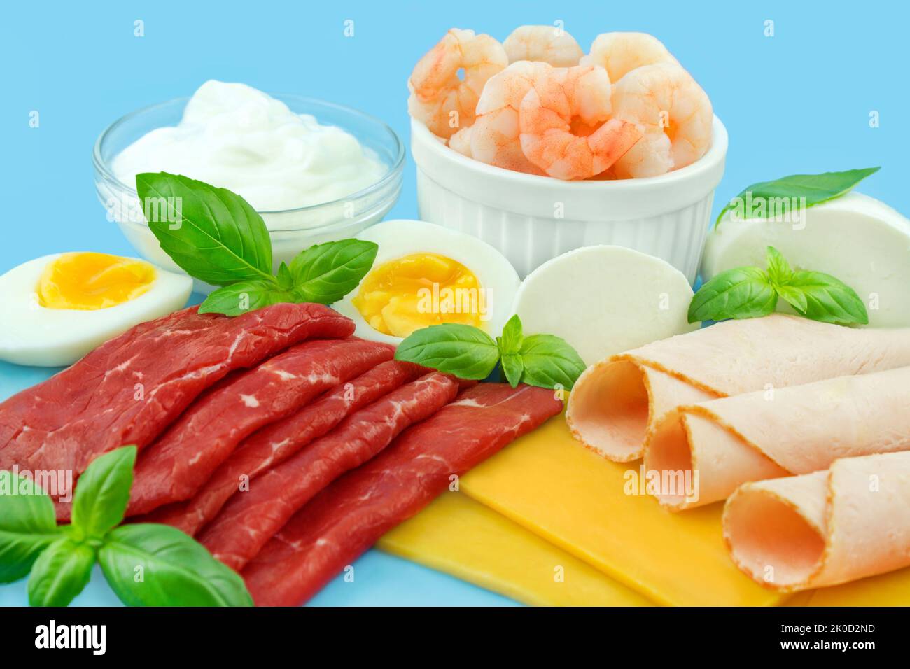 Proteinreiche Ernährung mit Fleisch, Käse, Ei, Joghurt und Shrimps auf blauem Hintergrund Stock Photo
