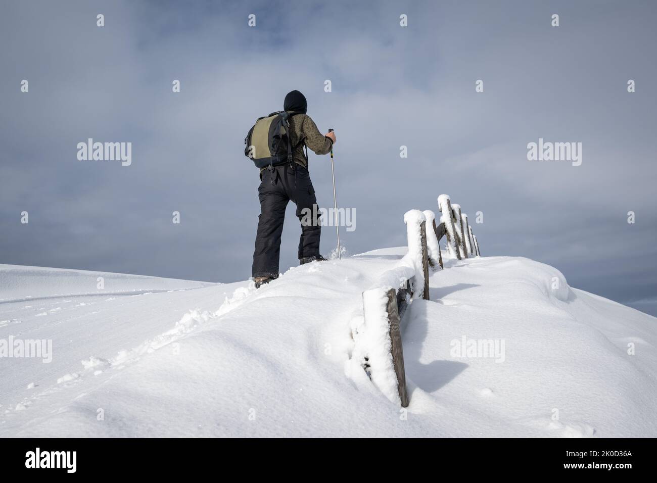 A man walking on the fresh snow, moody sky overhead. Stock Photo