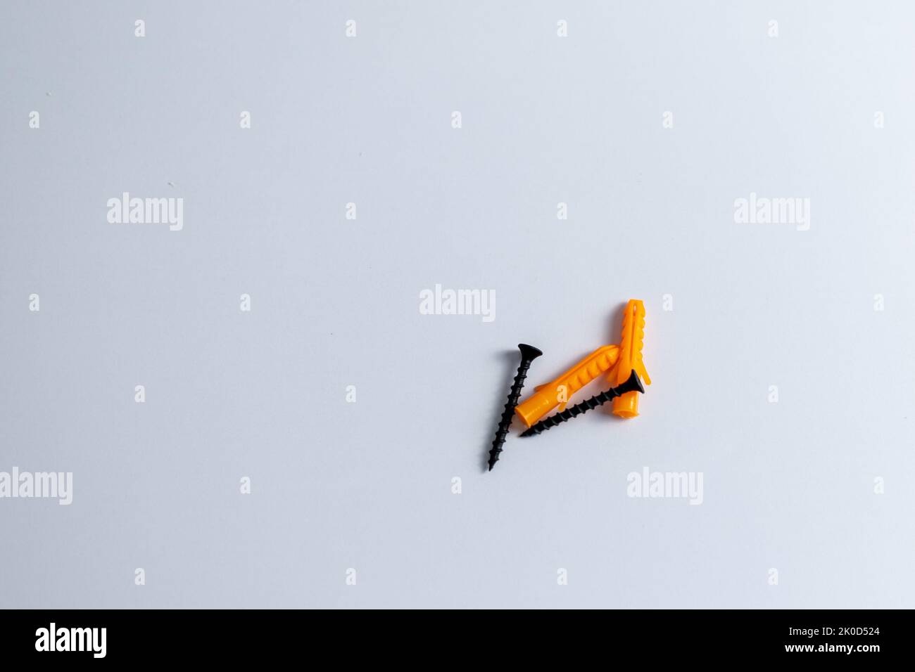 Black screw with plastic dowels plugs on isolated white background Stock Photo