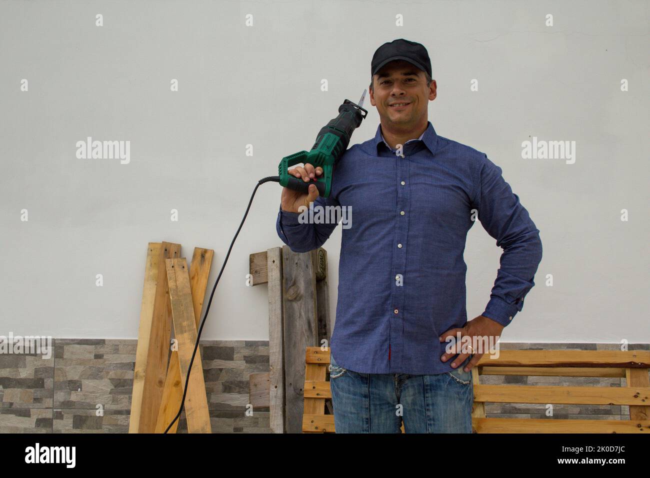 Guy Using Hacksaw smiling handyman with a hacksaw on his shoulder while cutting and ...