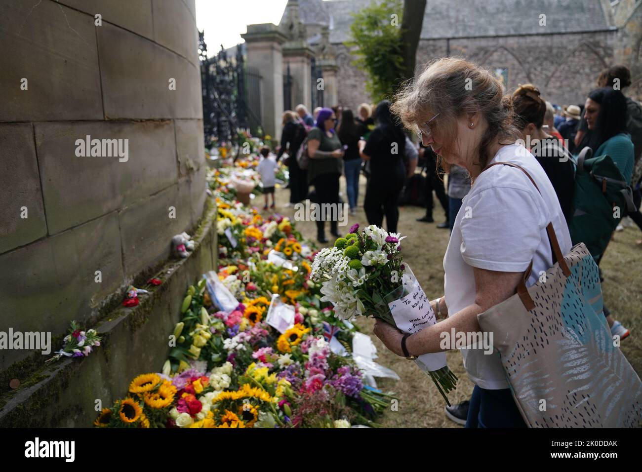 A woman lays flowers outside the Palace of Holyroodhouse in Edinburgh. Queen Elizabeth II's coffin is travelling from Balmoral to Edinburgh, where it will lie at rest at the Palace of Holyroodhouse. Picture date: Sunday September 11, 2022. Stock Photo