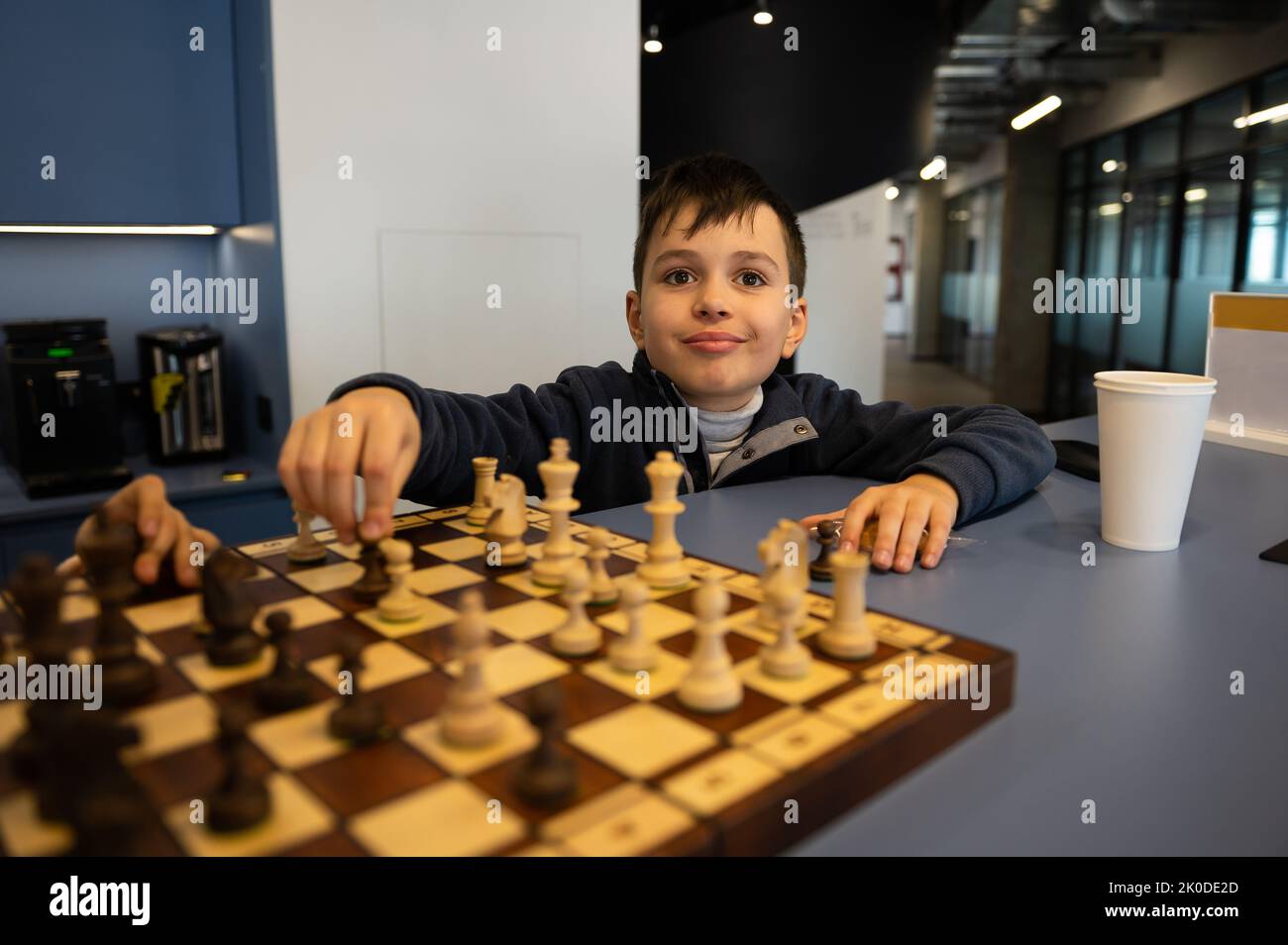 Smart Caucasian boy holding a chess piece and moving it on a chessboard ...