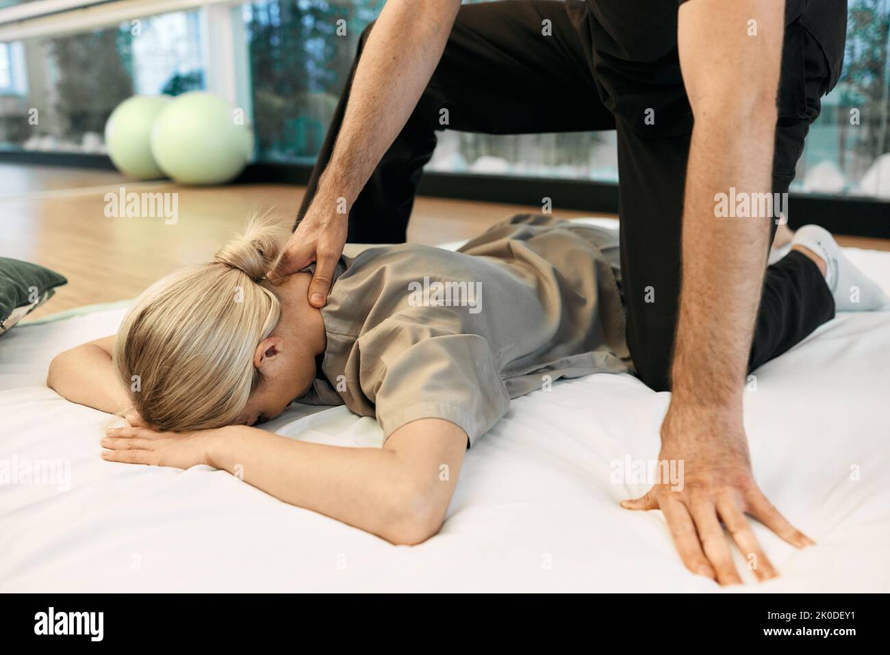 Female patient lying gymnastic mat receiving Yumeiho Japanese back and neck massage with alternative treatment specialist. Therapeutic massage Yumeiho Stock Photo