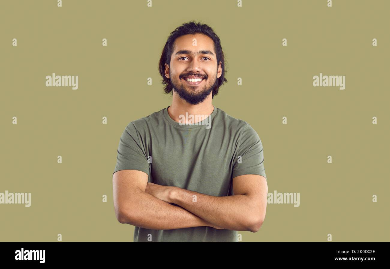 Portrait of happy young indian man with beautiful smile on khaki studio background. Stock Photo