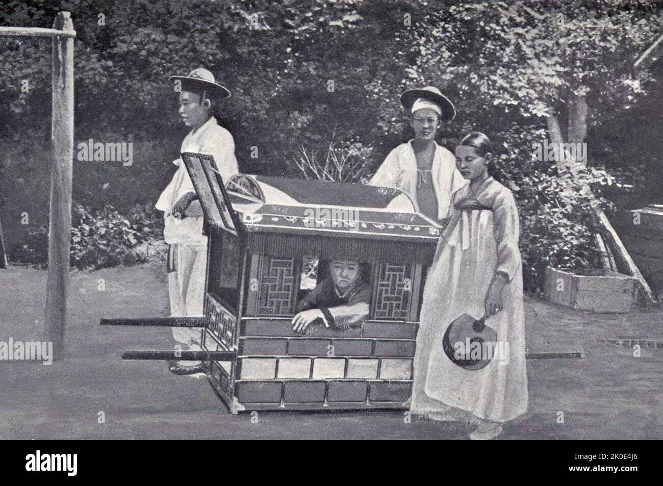 Joseon era aristocrat carried in a litter by two servants and escorted by a maid, Korea, 1900. Stock Photo