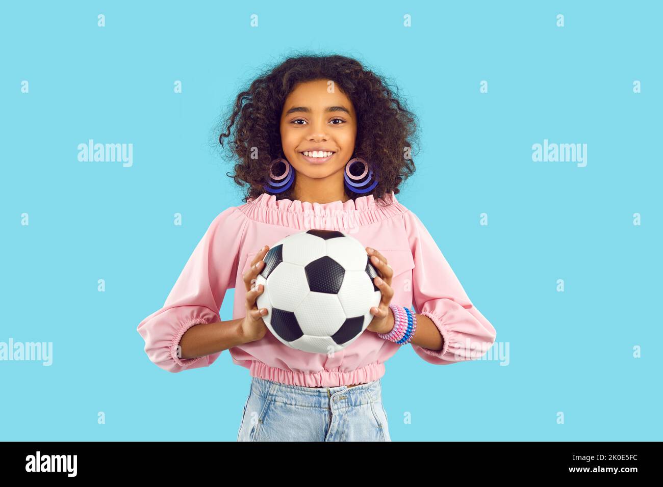Smiling biracial teen girl with football ball Stock Photo