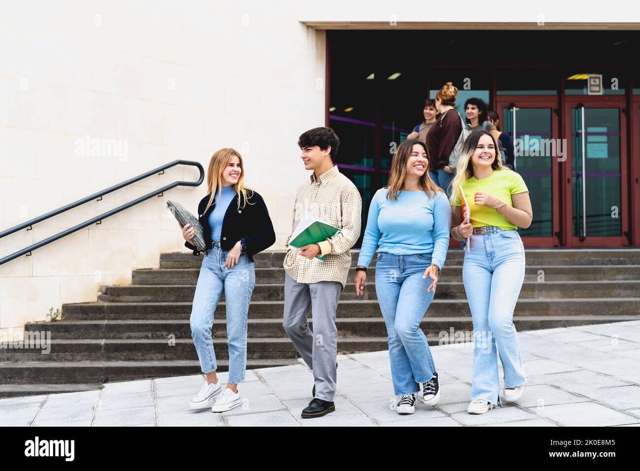 Young diverse students leaving university after lesson - Youth and education concept Stock Photo