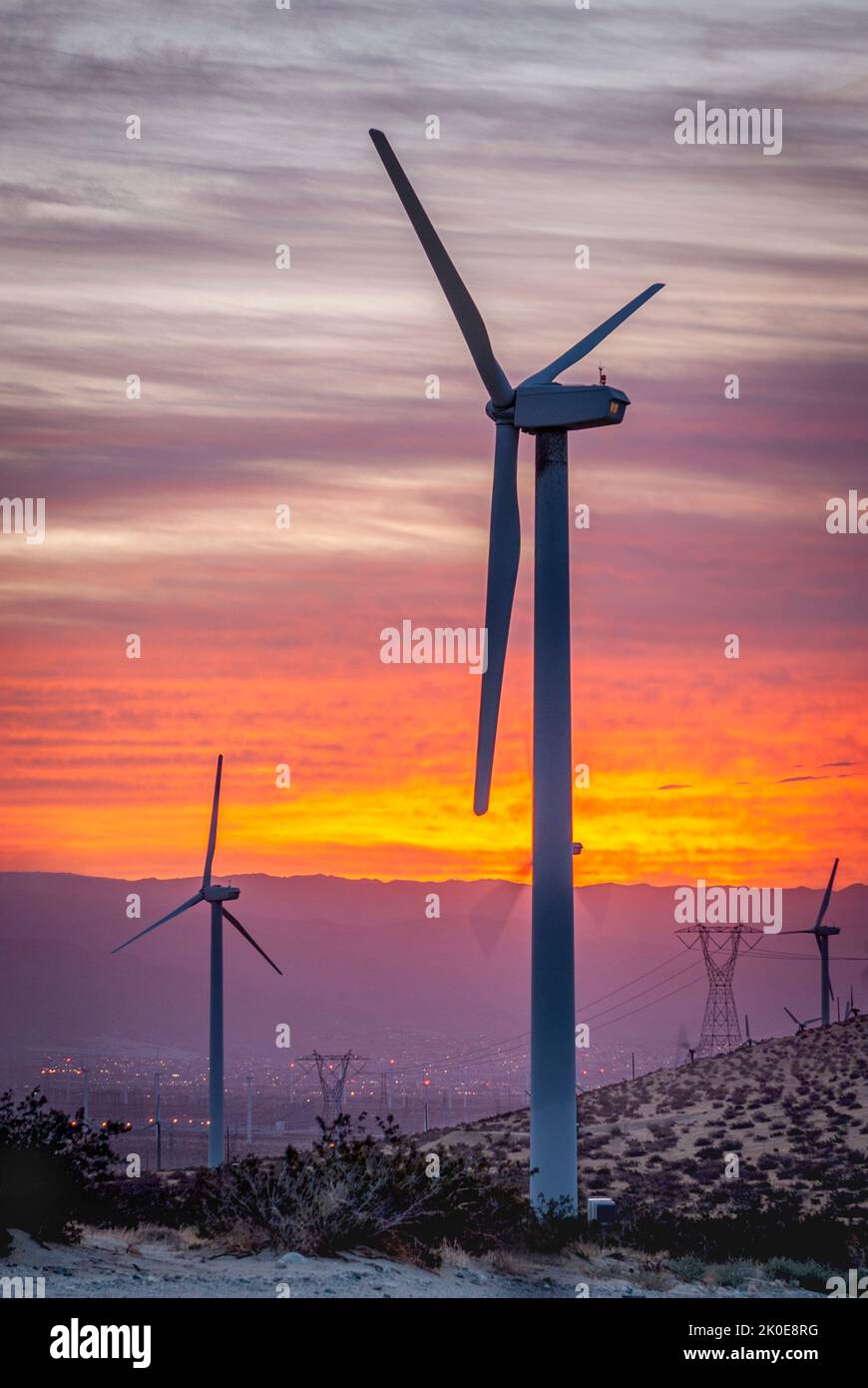 A wind generating turbine propellers await wind to form through a canyon as the sun rises to produce renewable energy. Stock Photo