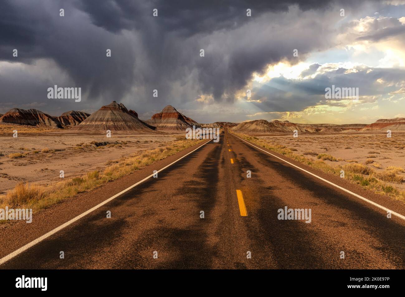 The remote roadway deep in the heart of the Petrified Forest National Park shows the beautiful mountain scenery framed against a stormy sky with rain Stock Photo