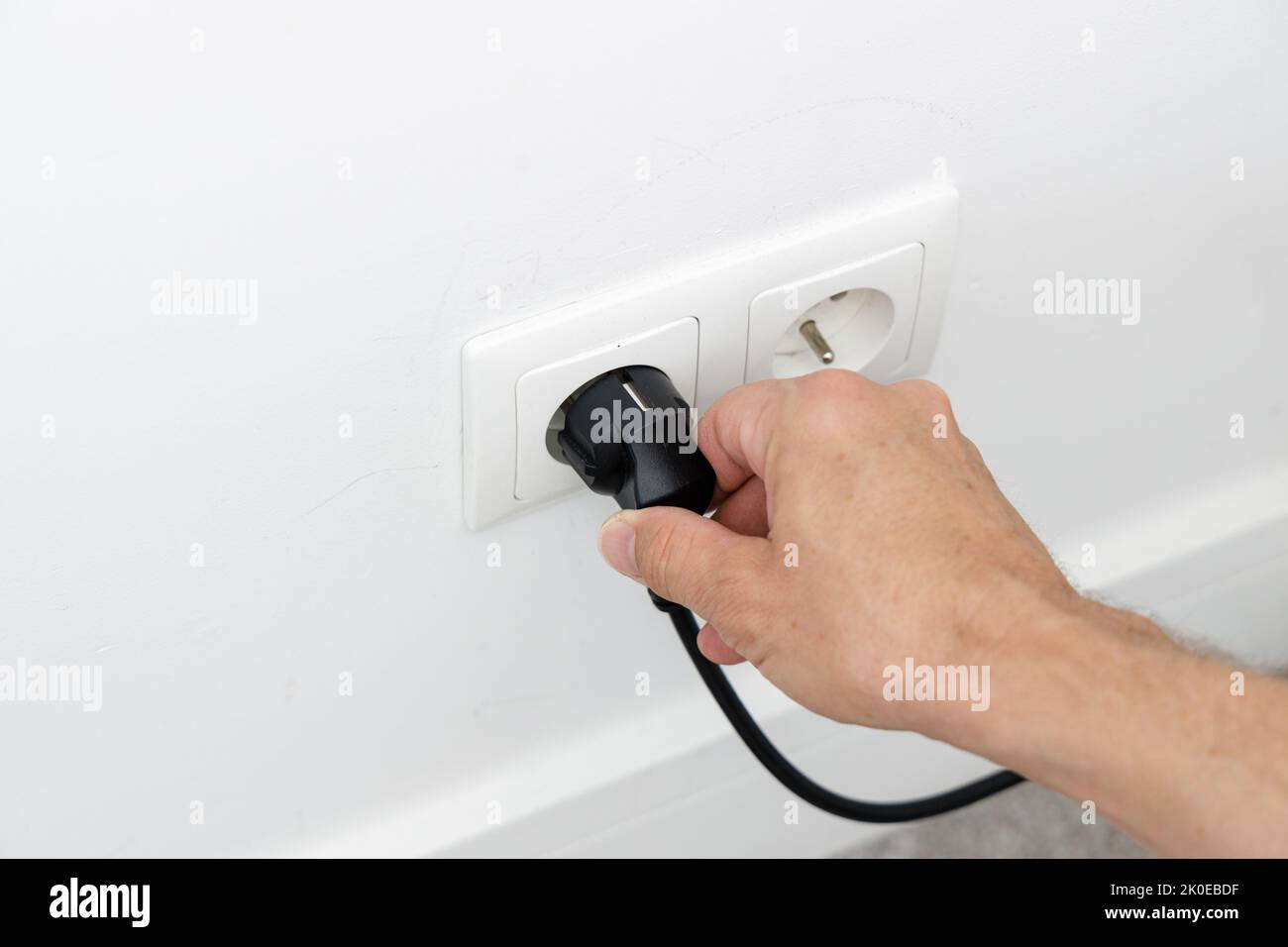 Saving energy at home, removing the plug from the socket Stock Photo