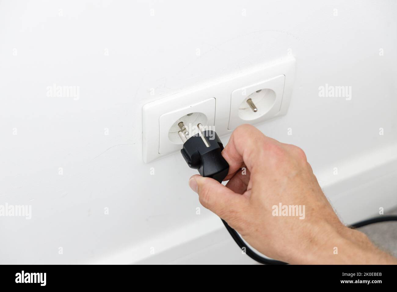 Saving energy at home, removing the plug from the socket Stock Photo