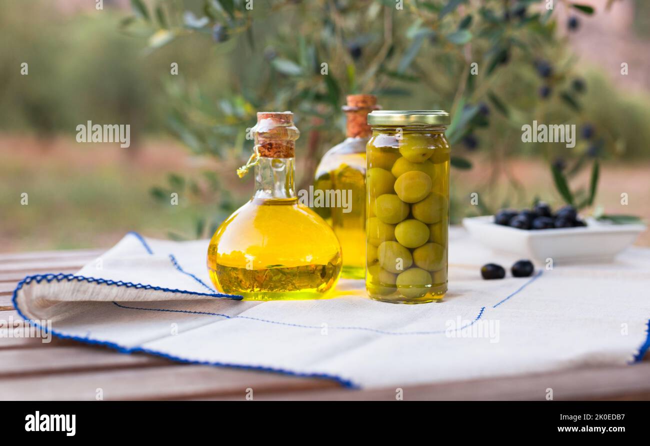 olive oil in a glass bottle and ripe black olives on the background of ...