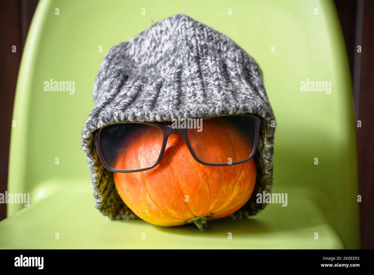 Pumpkin in winter hat on Halloween at cold home, no gas and electricity for heating, single funny vegetable is freeze. Concept of energy crisis, expen Stock Photo