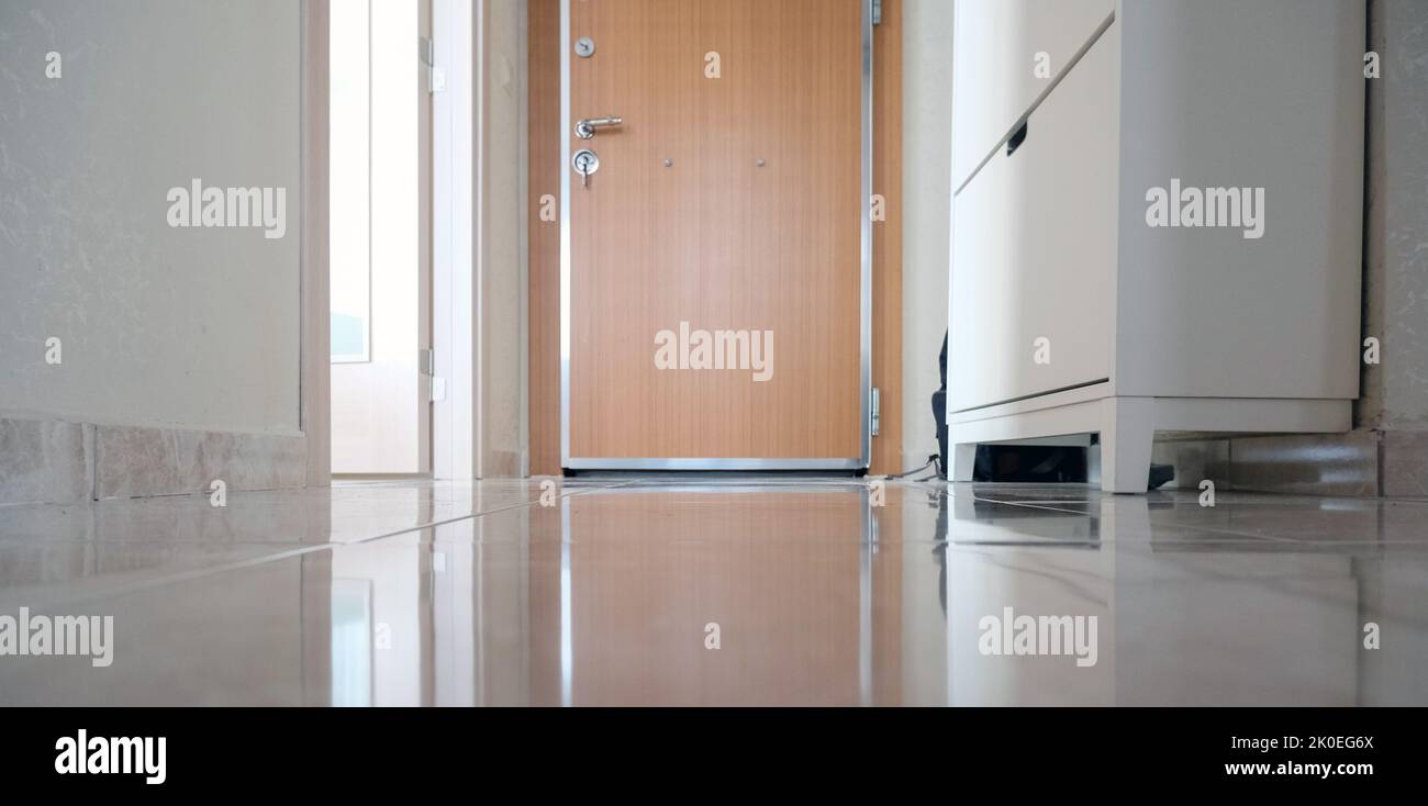 The door, an ikea shoe rack on white tiles, a steel door, a minimalist