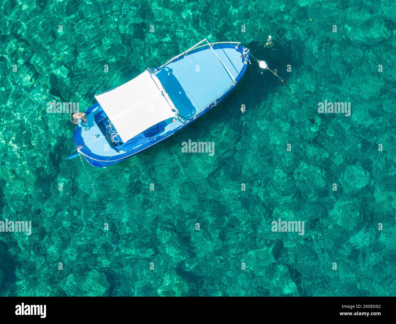 Aerial view of floating boat moored on a transparent sea. Relax on the Ionian Sea. Bathers. Corfu island, Limni beach Glyko. Greece Stock Photo