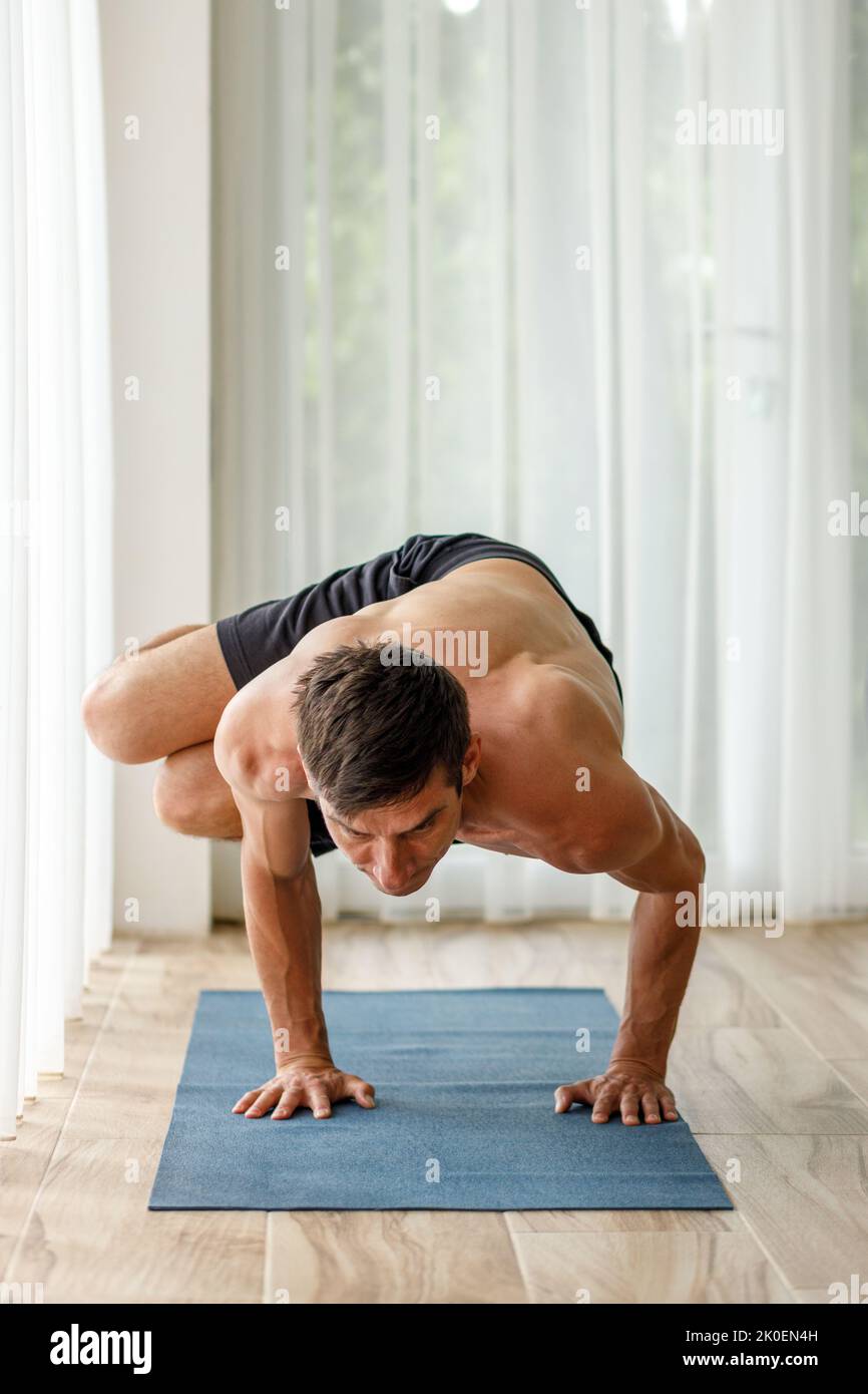 Middle-aged man doing side bakasana yoga pose during his morning ...