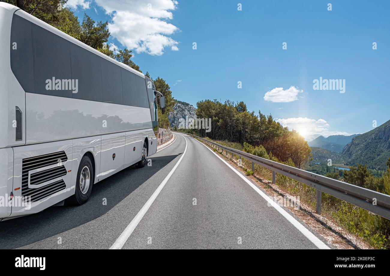 A white bus rides along the highway against the backdrop of a beautiful ...