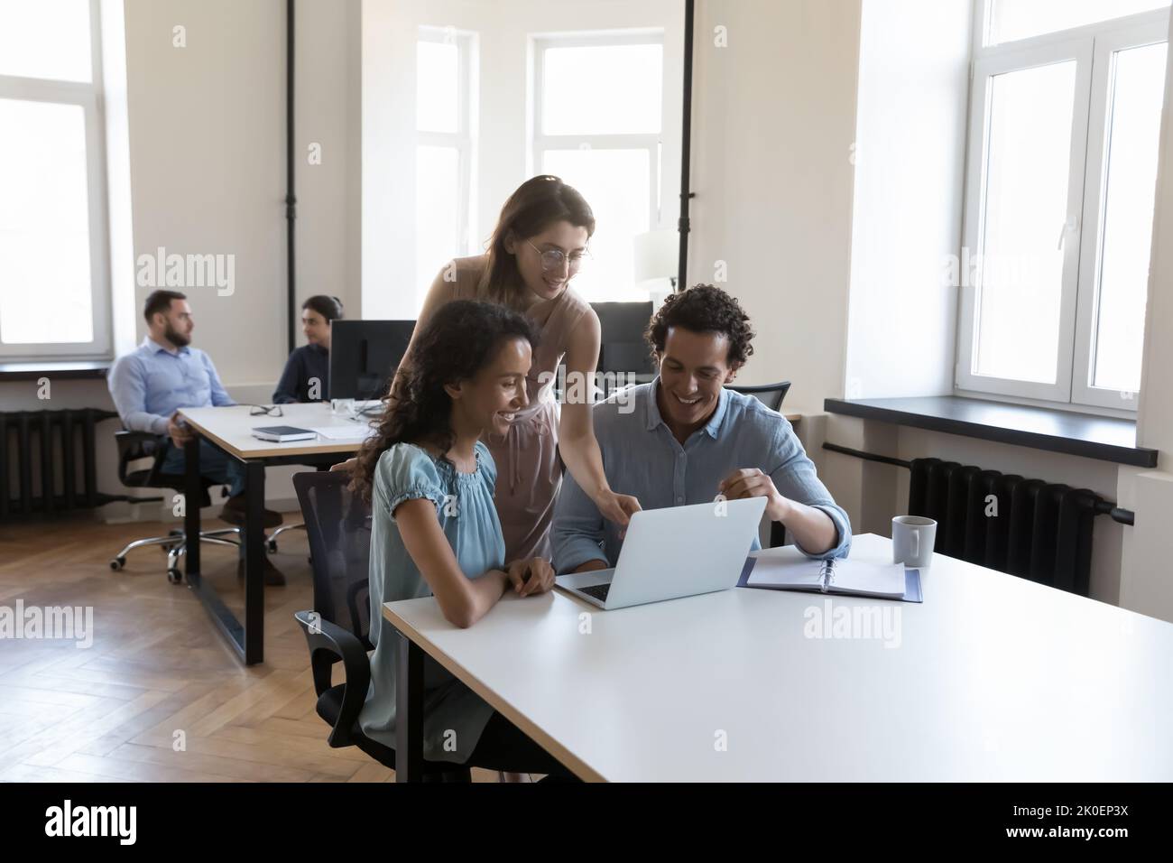 Diverse group of cheerful employees sharing computer at office table Stock Photo