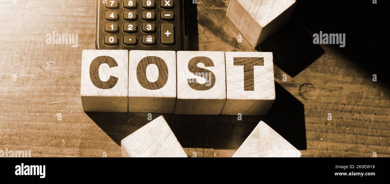 Wooden cubes foorming word COST and calculator. Cost, expense or