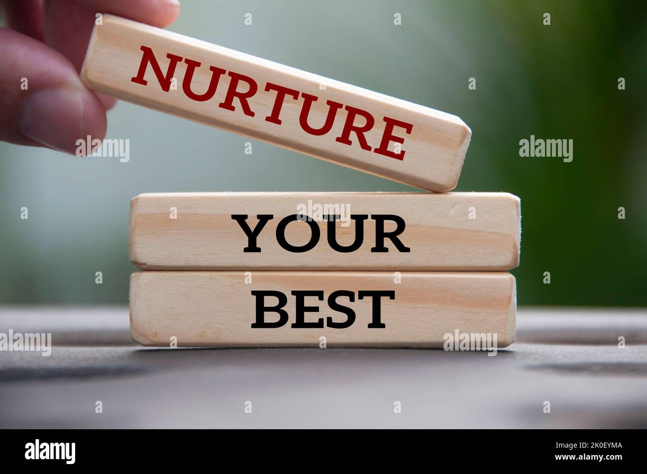 Hand holding wooden block with text - Nurture your best. Motivational concept. Stock Photo