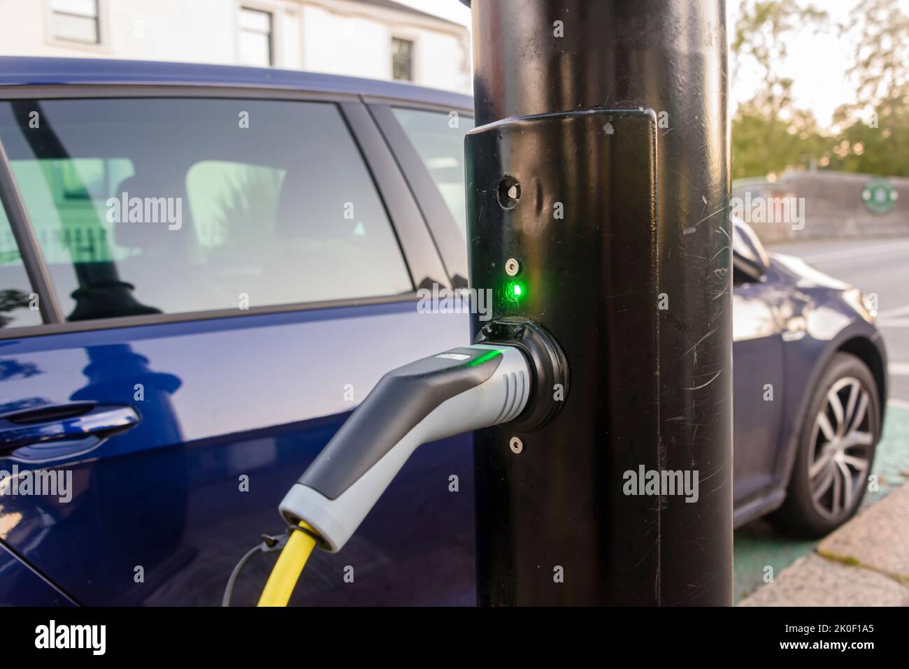 Electric car being charged from a charging point on a street light post. Stock Photo