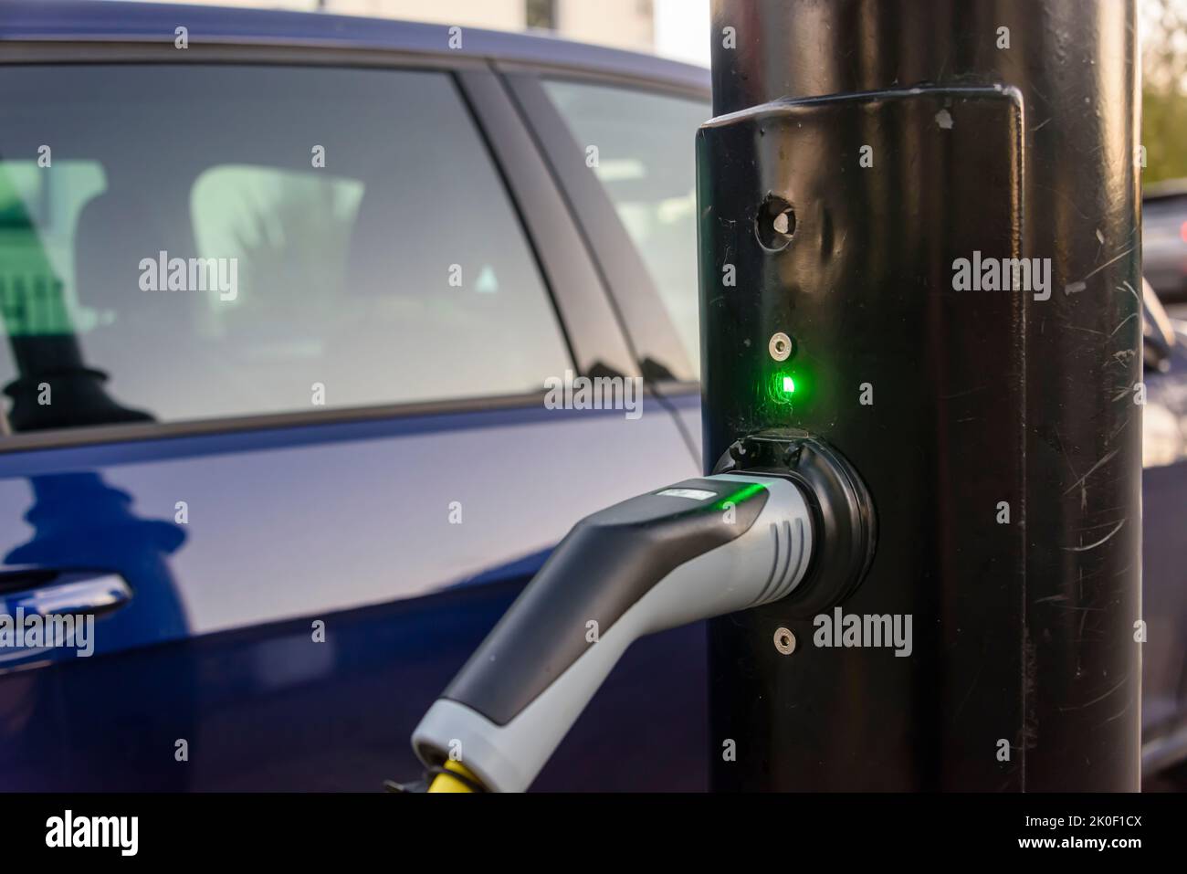 Electric car being charged from a charging point on a street light post. Stock Photo