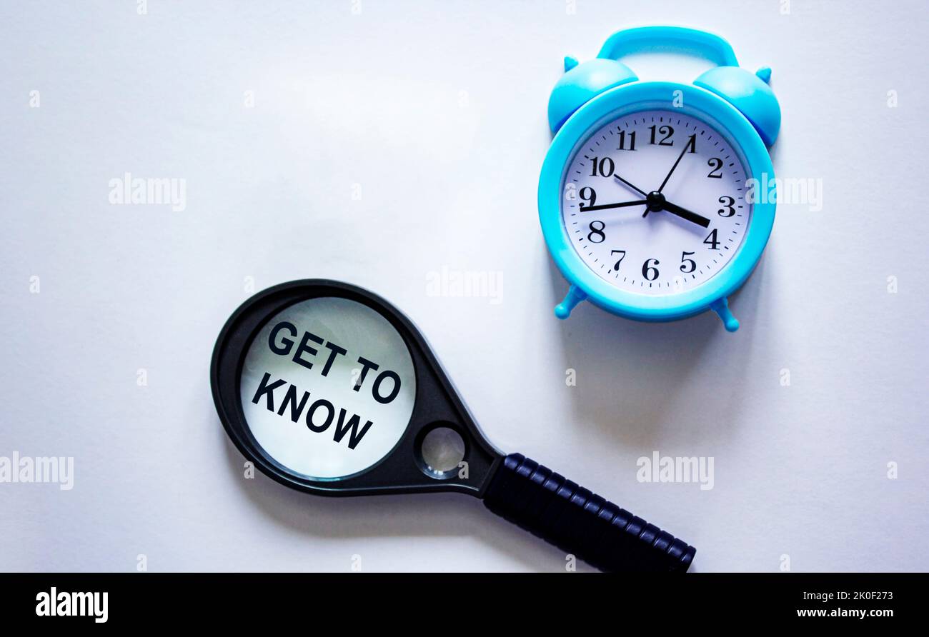 Get to know written on a magnifying glass and a white background with a clock. Stock Photo