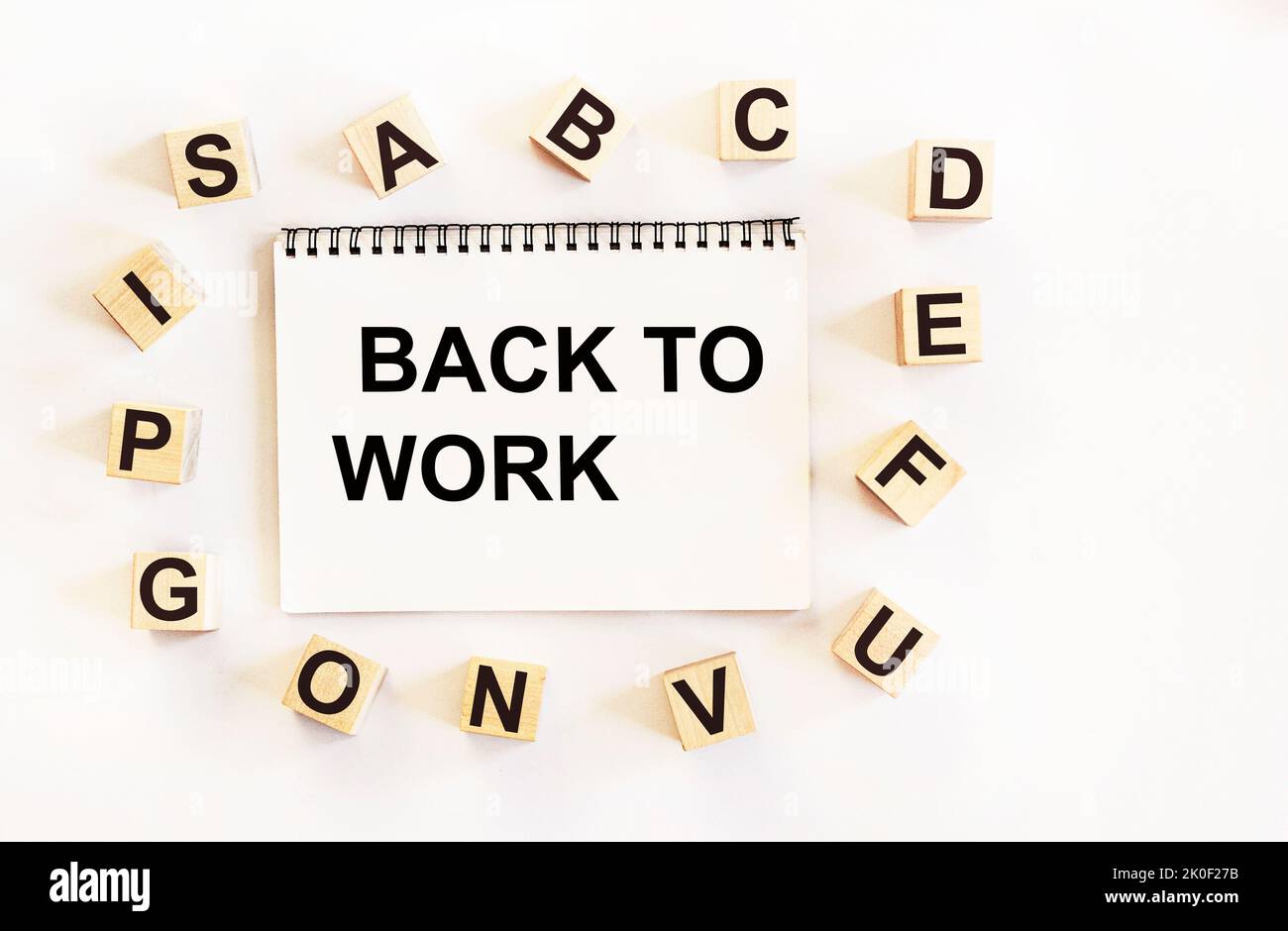 Notepad on a white background with cubes with the alphabet and the text back to work written on it Stock Photo