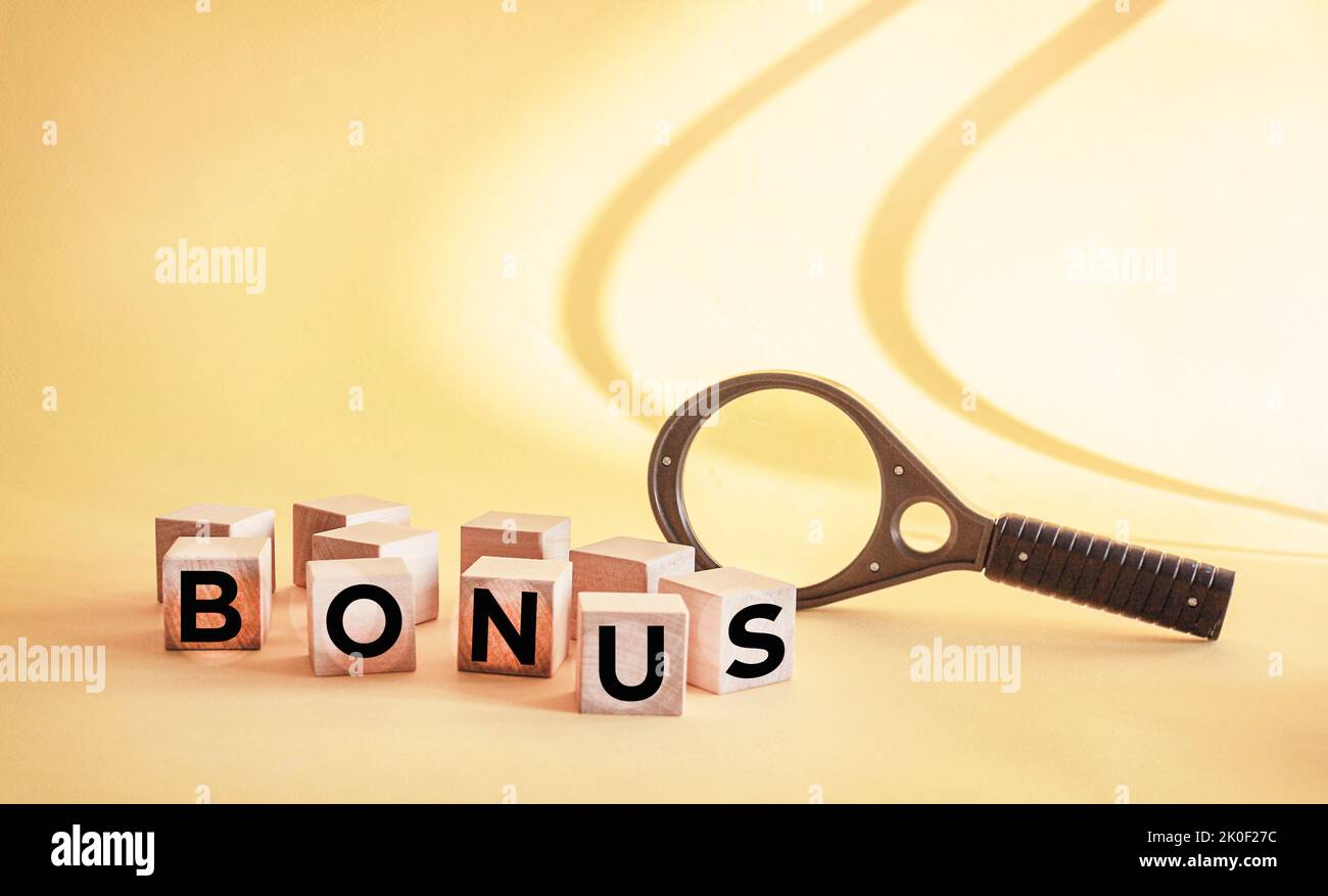 BONUS word made from building blocks on vintage background with magnifying glass in the background Stock Photo
