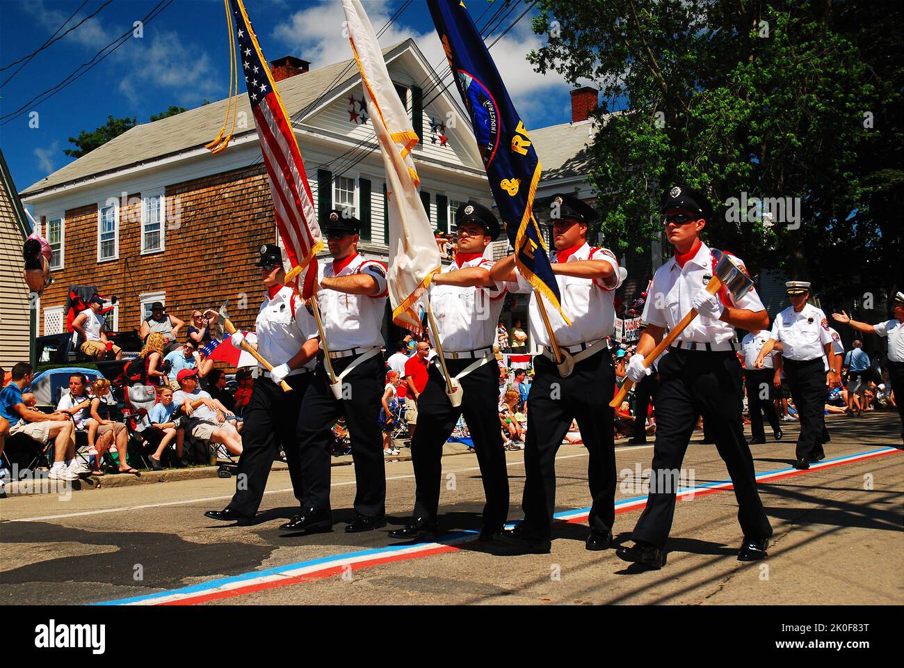 Uniformed fireman march in a Fourth of July Parade through the streets
