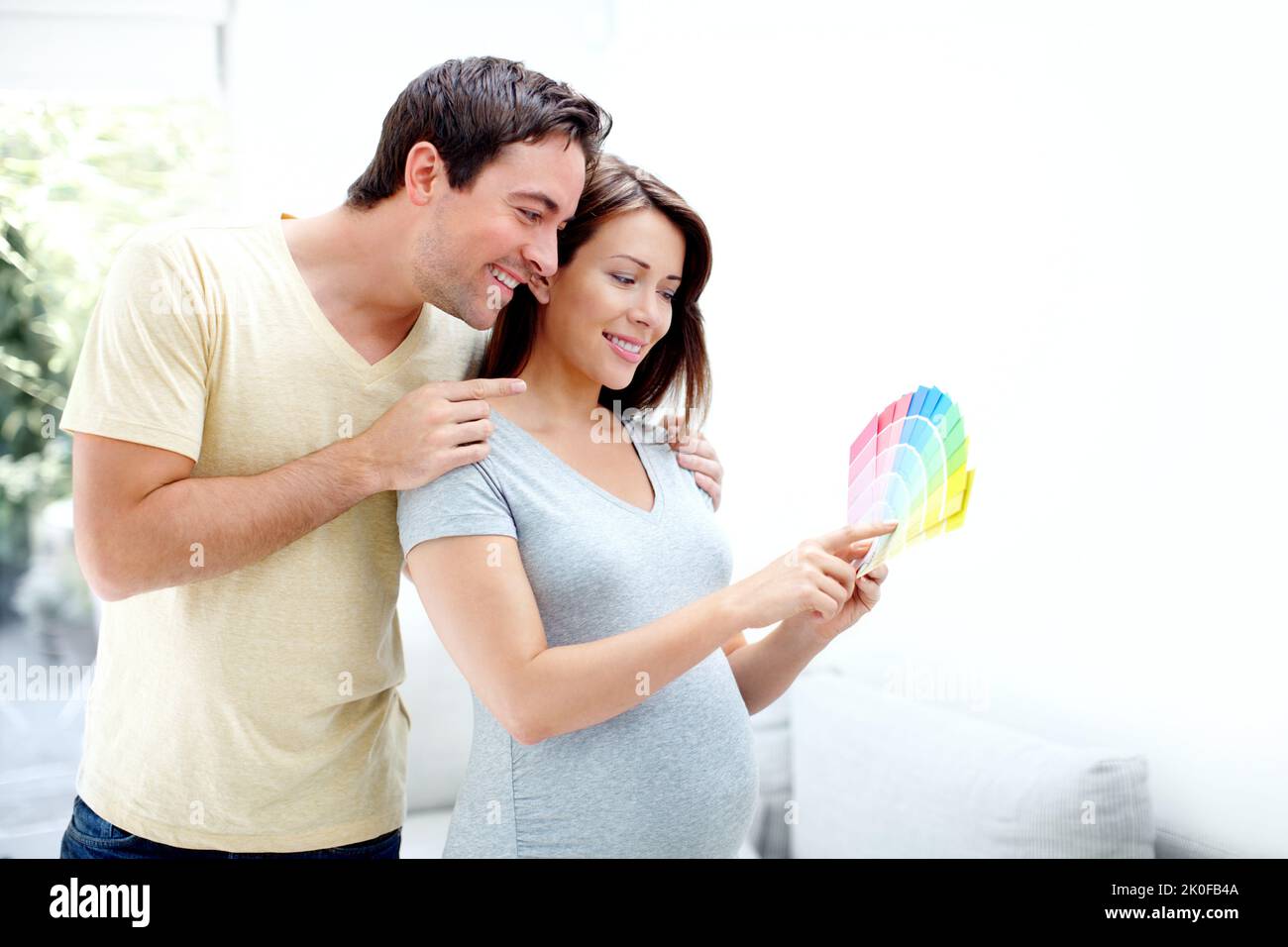 Beginning of the exciting jouney. Happy parents to be, picking out the right colour for their babys room. Stock Photo