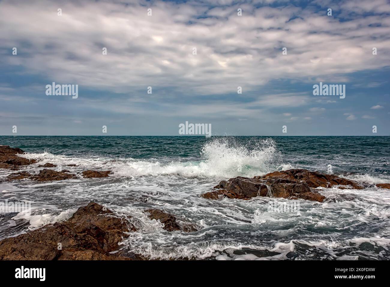 The stunning seascape with the cloudy sky and sea waves at the rocky coastline of the Black Sea Stock Photo