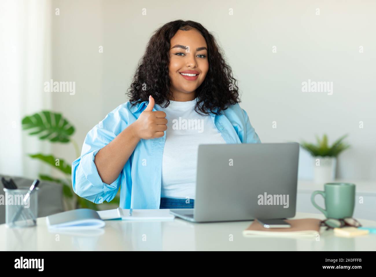 African Businesswoman Using Laptop Gesturing Thumbs Up In Modern Office ...