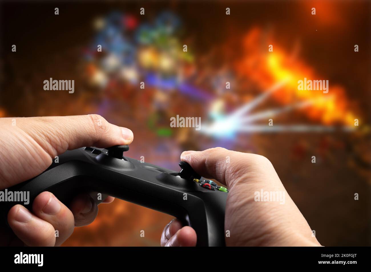 A gamer plays a video game on the screen of a large plasma TV. He has a GAM22ICB gamepad in his hands. Youth culture, online games, competitions, tour Stock Photo