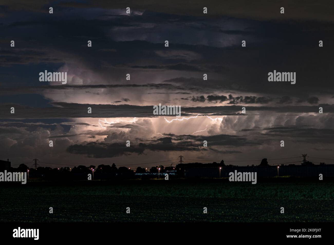 A Cumulonimbus storm cloud is lit up by lightning at night Stock Photo
