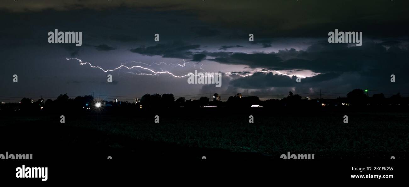 Long horizontal bolt of lightning cleaves the night sky during an autumn thunderstorm Stock Photo
