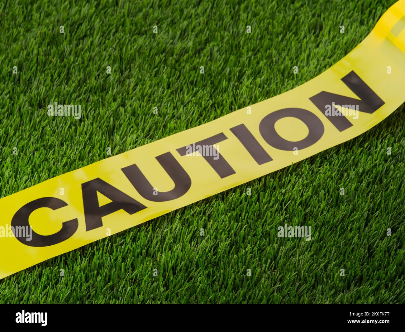 Yellow tape with the inscription - caution. Isolated on a green background. Barrage, warning about caution, attentiveness. Destroyed roads, buildings, Stock Photo