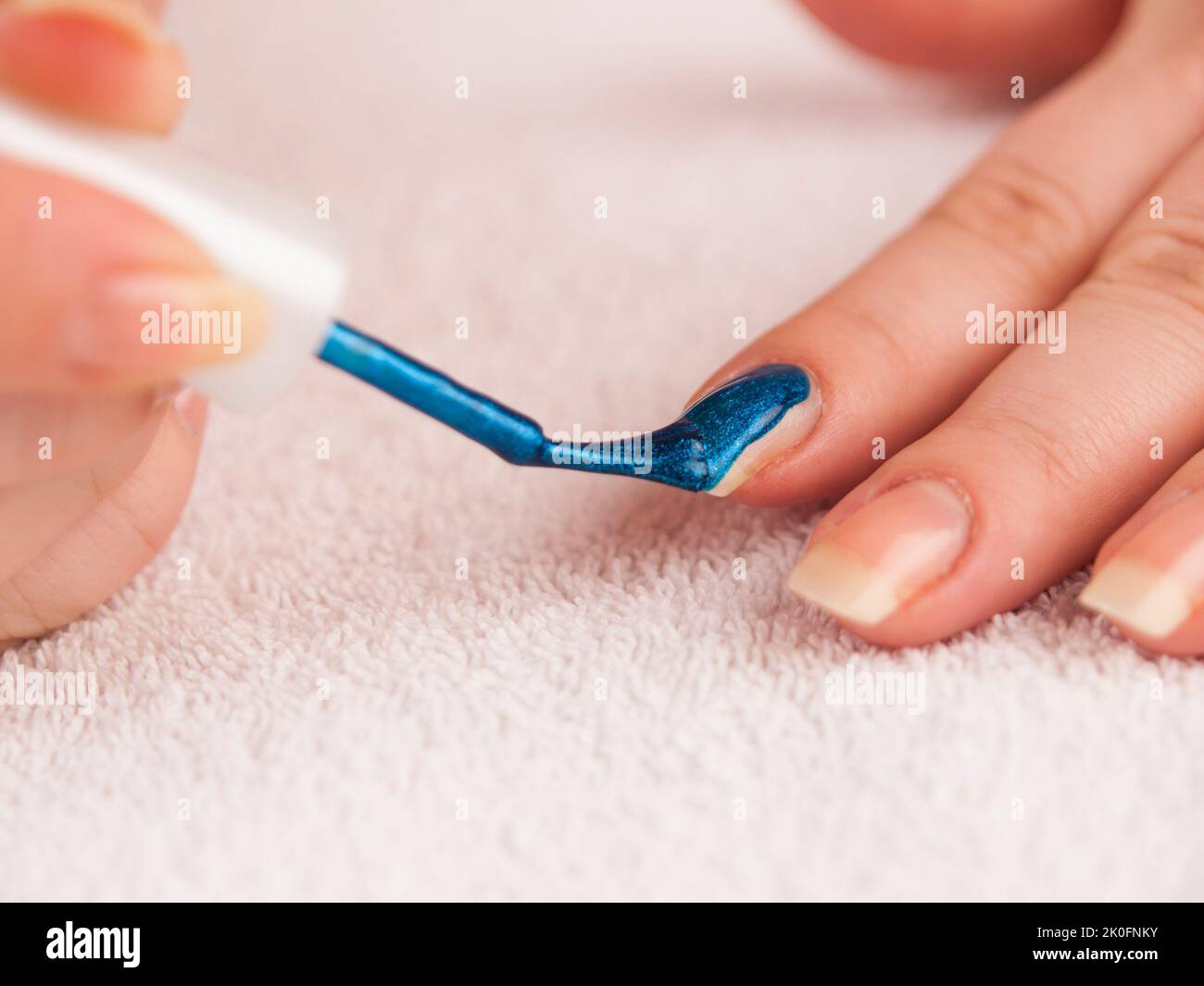 Woman applying dark blie shiny nail polish on forefinger Stock Photo
