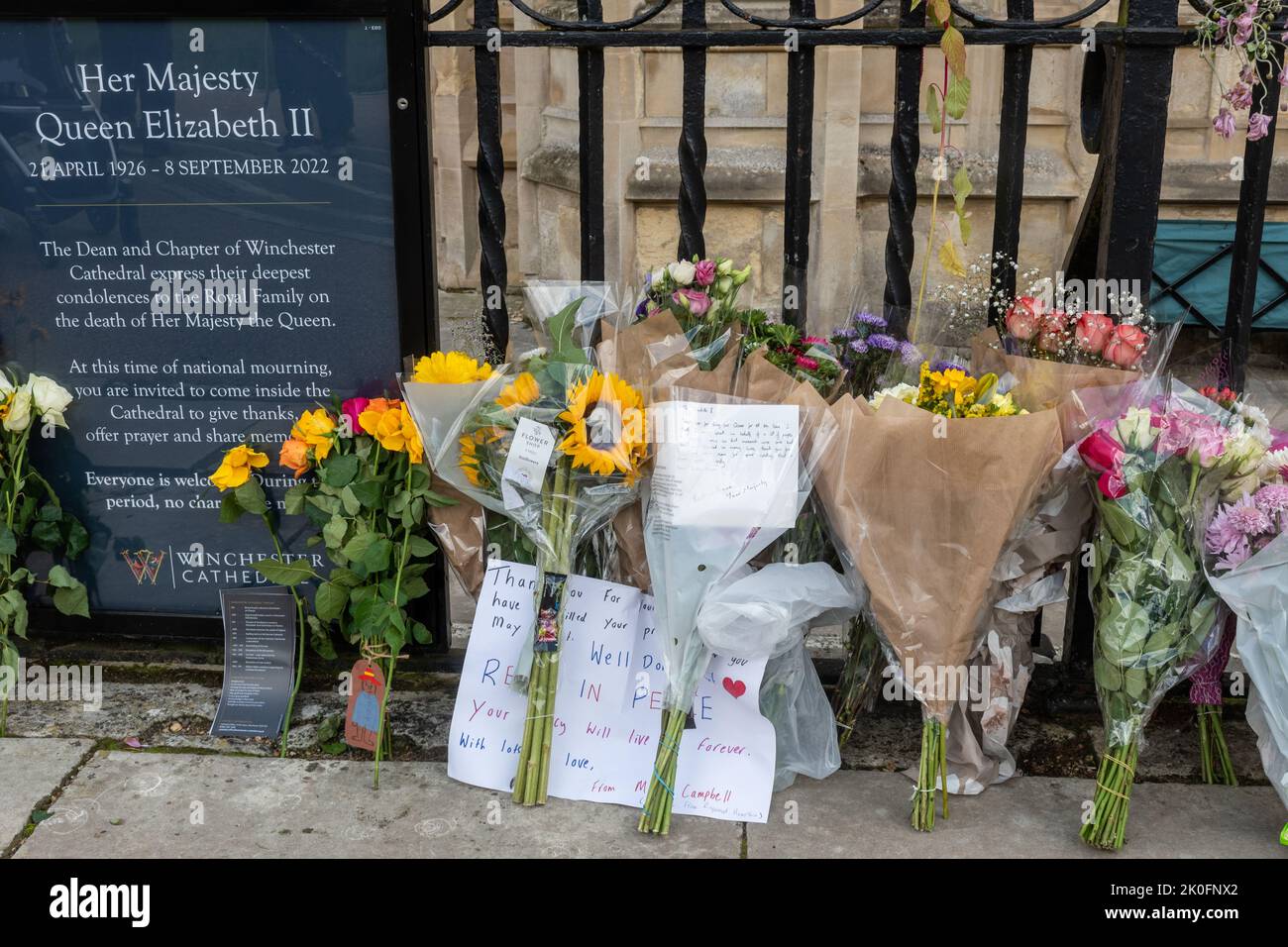 Winchester, Hampshire, UK. 11th September 2022. Following the death of Queen Elizabeth II on 8th September 2022, people have placed flowers and tributes in honour of Queen Elizabeth II outside the entrance to Winchester Cathedral. The country is in a period of national mourning until her funeral. Stock Photo