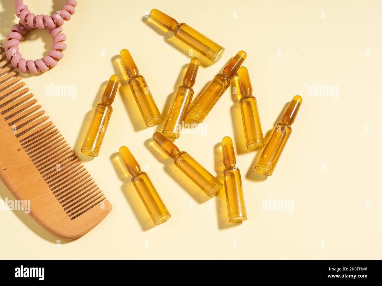 Group, set Cosmetic ampoules with serum for hair growth, restoration. Hair comb, Spiral Hair Ties on a beige background. Concept beauty hair, Self-car Stock Photo