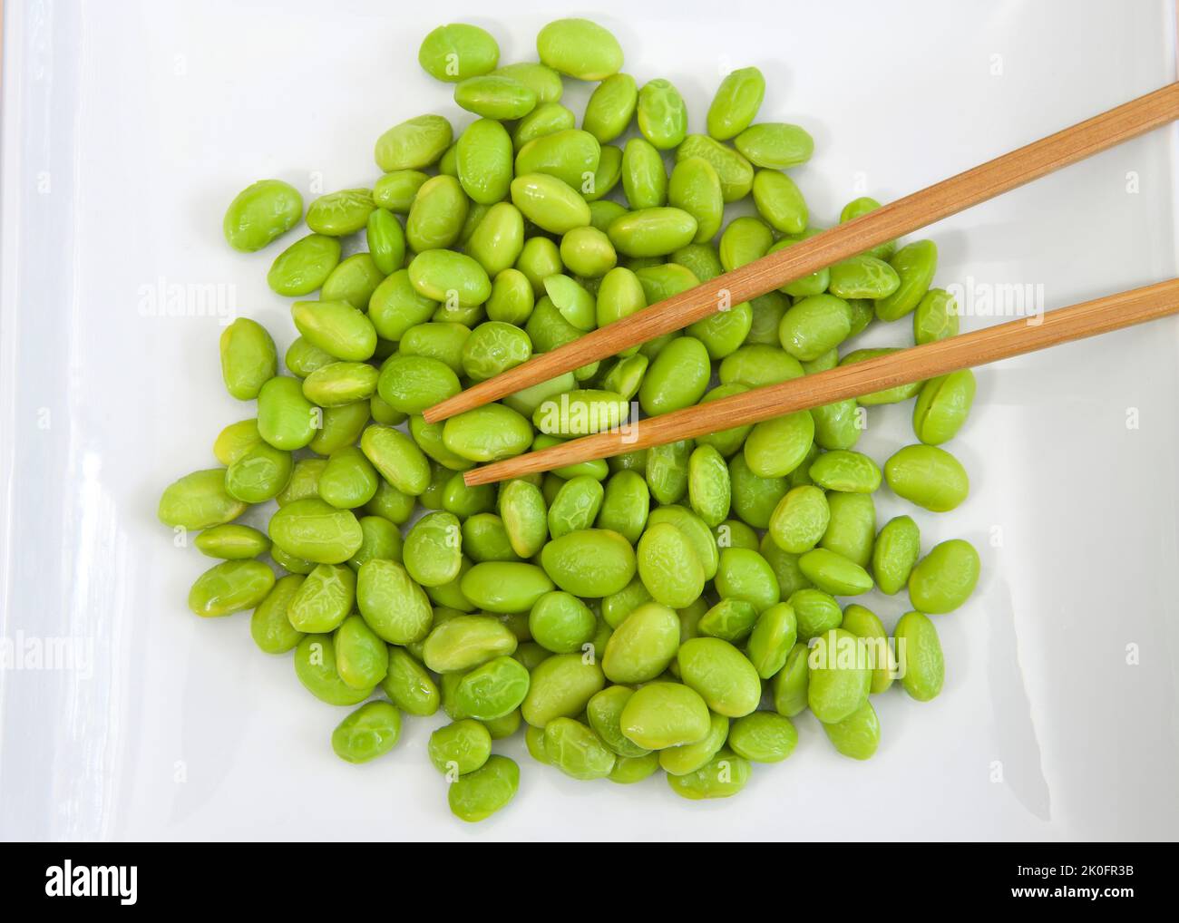 Top view over pile of shelled edamame beans on a white porcelain plate