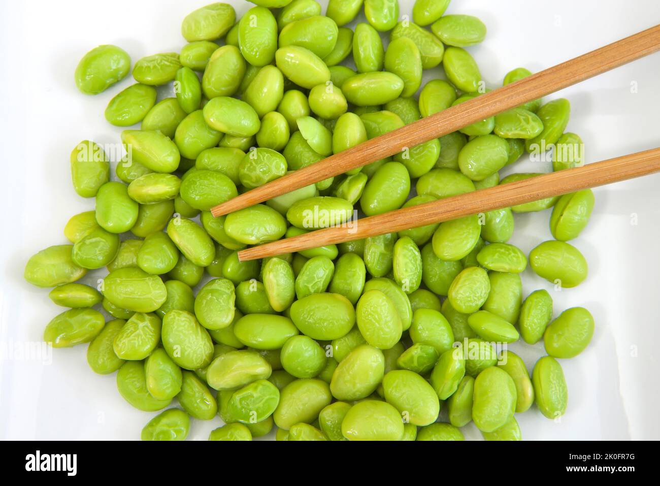 Top view over pile of shelled edamame beans on a white porcelain plate