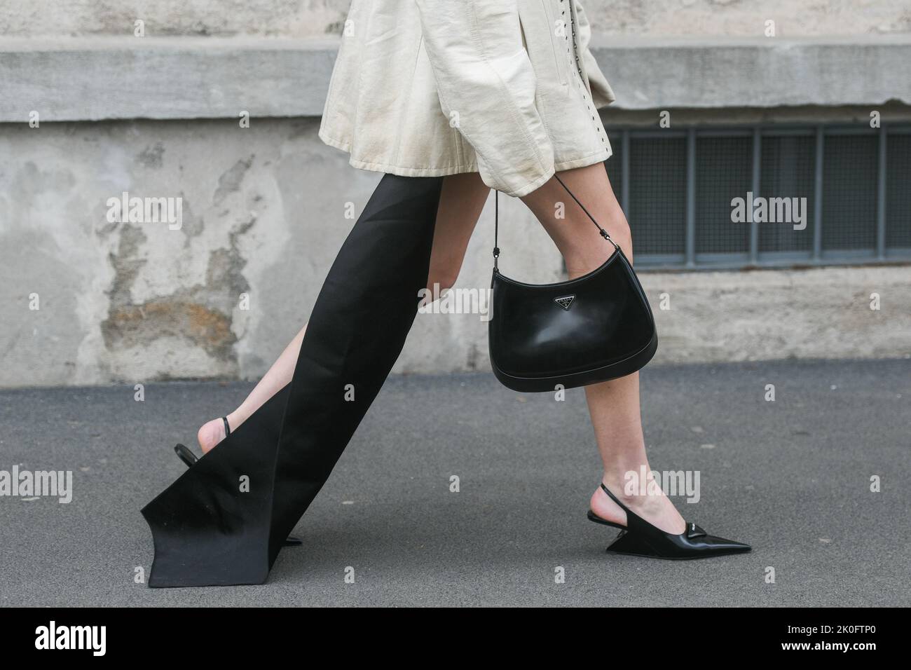 Milan, Italy - February, 24: Street style, woman wearing cream leather jacket, mini skirt with long train, black Prada bag and Prada heels. Stock Photo