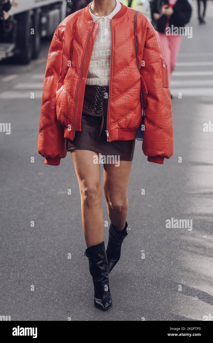 Milan, Italy - February, 24: Street style, woman wearing red shiny leather crocodile print puffer jacket and black shiny leather heels ankle boots. Stock Photo